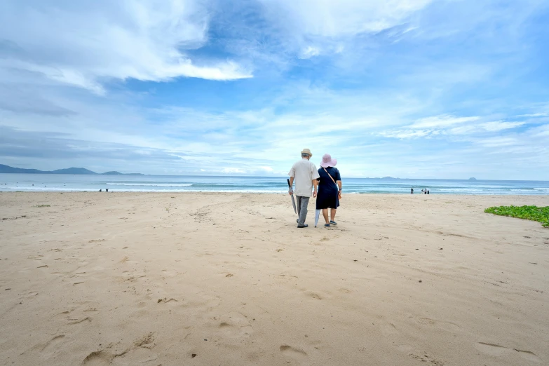 two people standing on the beach, watching the water