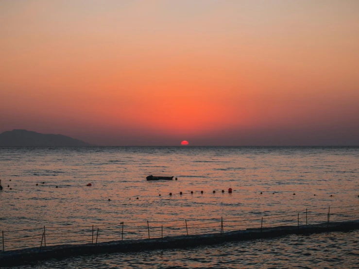 a boat floating in a large body of water at sunset