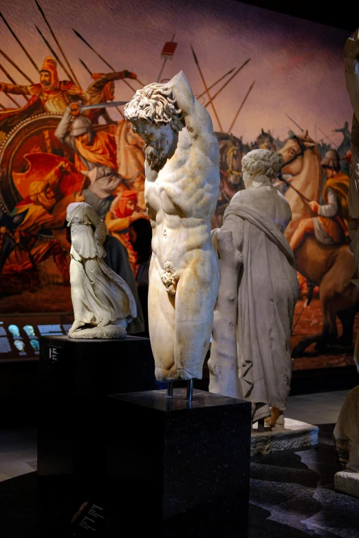 white statues on pedestals and in front of an ornate painting