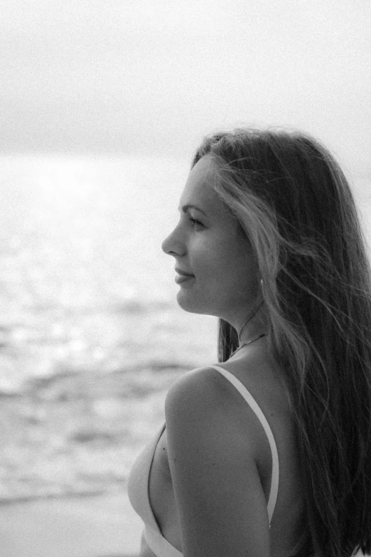 a woman sitting by the water with long hair