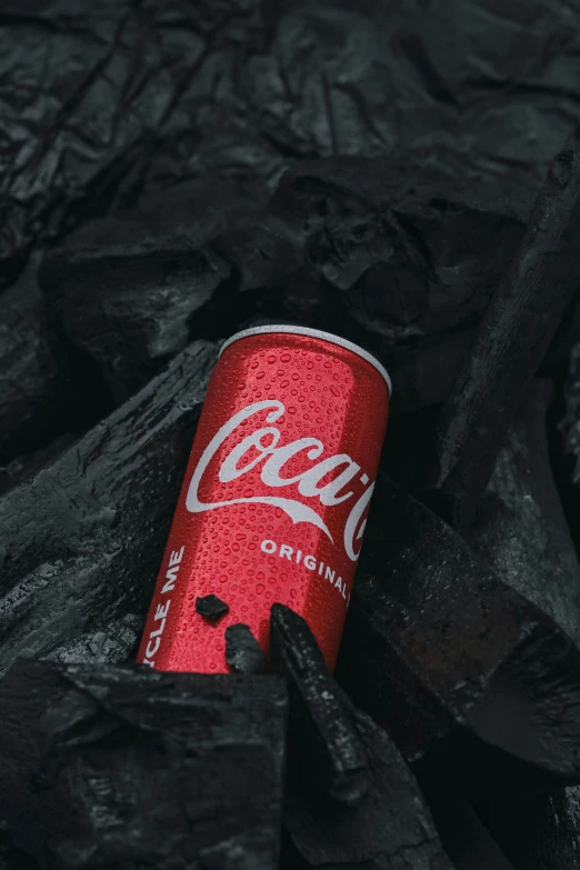 a can of coca cola sitting on top of coal