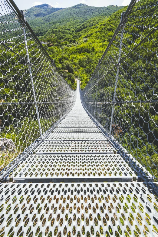 a man on a chain linked walkway over rocks