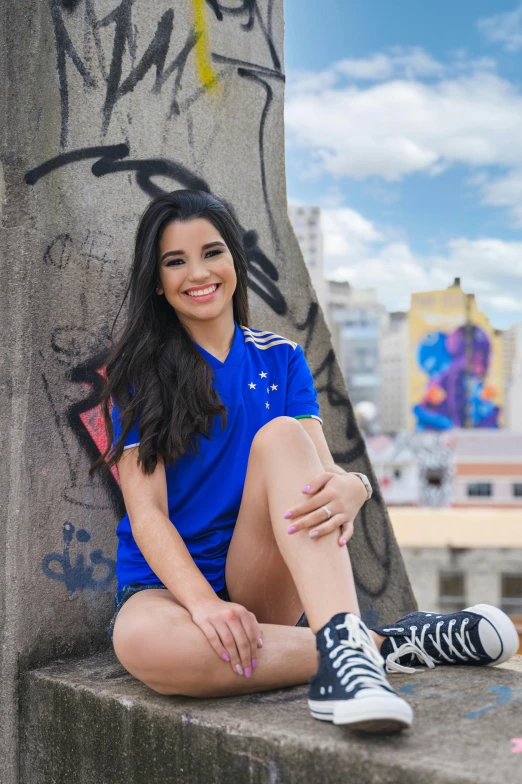 a girl is sitting against the corner of a wall covered in graffiti