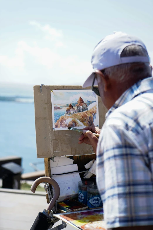 an old man holding up an artwork while standing in front of a painting