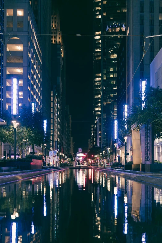 a city at night with many buildings and a pond in the center