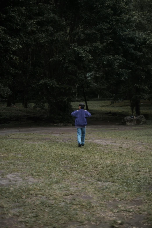 a man in a jacket walking toward a kite flying over his head