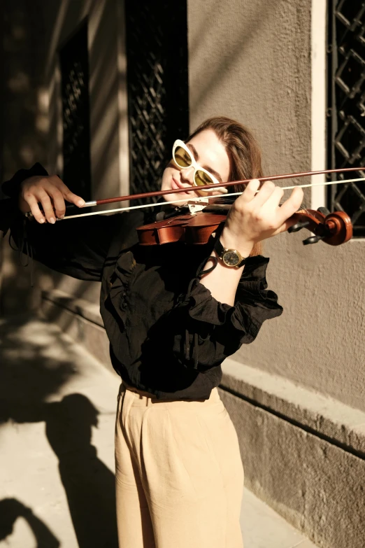 a woman is playing a violin on a sidewalk