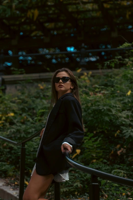 a woman is leaning on a rail with sunglasses on