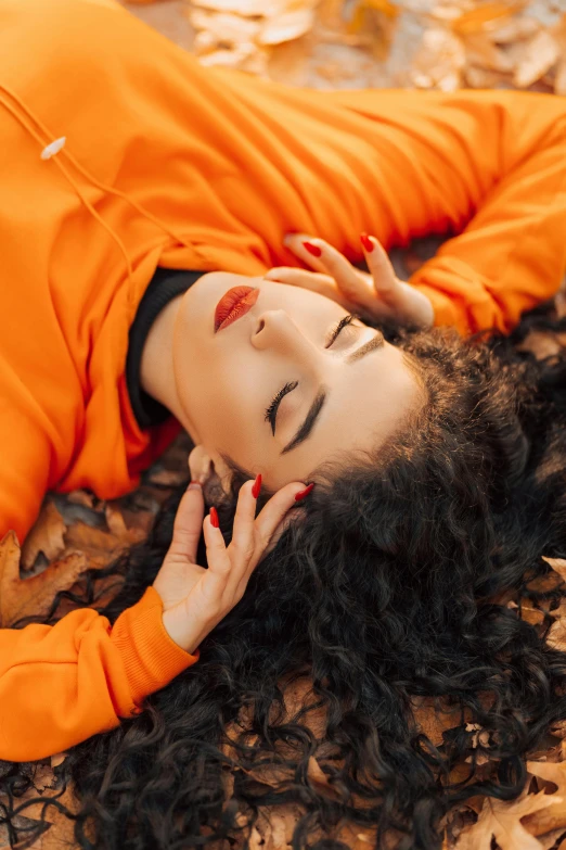 a woman laying down in the leaves with her hand on her face