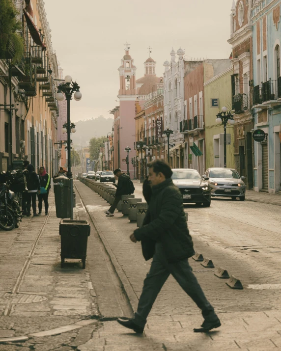 a man in a gray jacket walking down a sidewalk