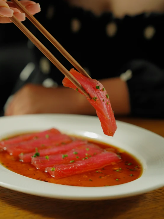 a person holding chopsticks above a plate of food