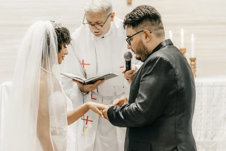 a bride and groom exchanging vows in front of the priest