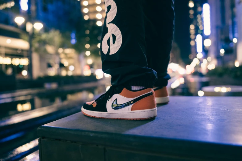 a man in black and orange sneakers standing on a bench