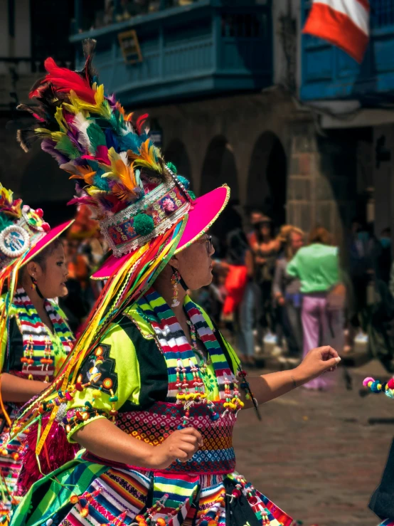 two people are wearing brightly colored headdress as they ride through the street