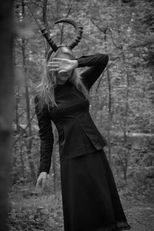 a woman wearing an horned hat standing in the woods