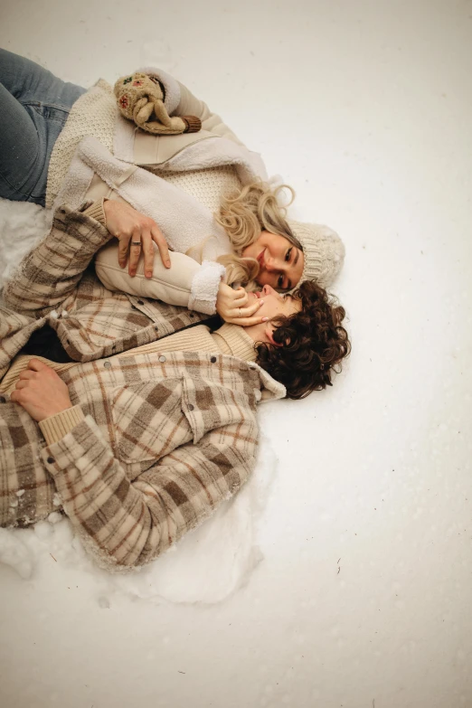 two women laying on top of each other in the snow