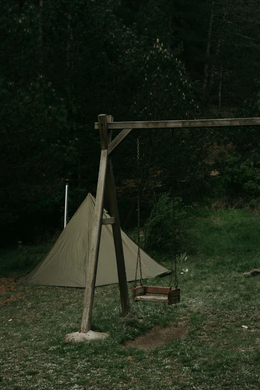 a wooden swing and a teepee set up in the grass