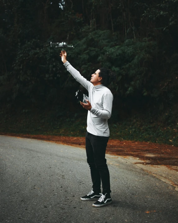 man holding a small bird on the street with a forest in background