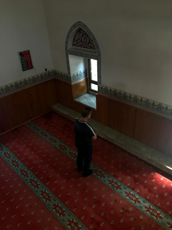 a man standing in a room looking down at a carpet