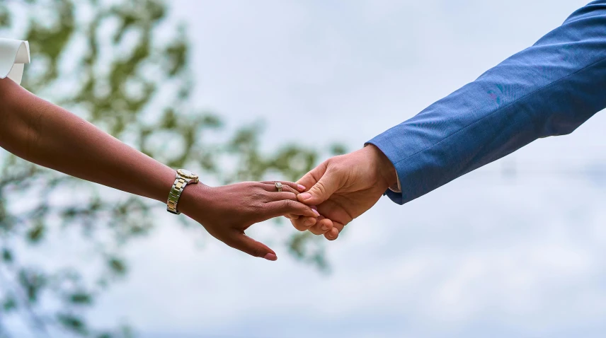 two people hold hands together while they walk