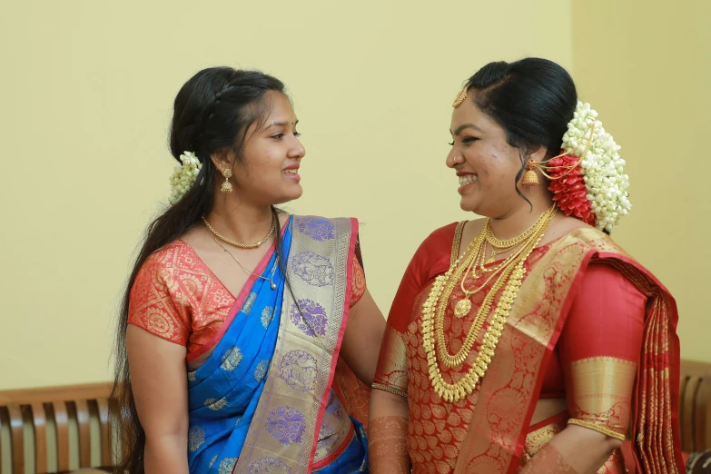 two women dressed in saris are posing for the camera