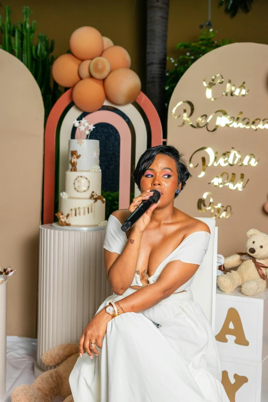 woman in a white dress sits on a chair while talking on a phone