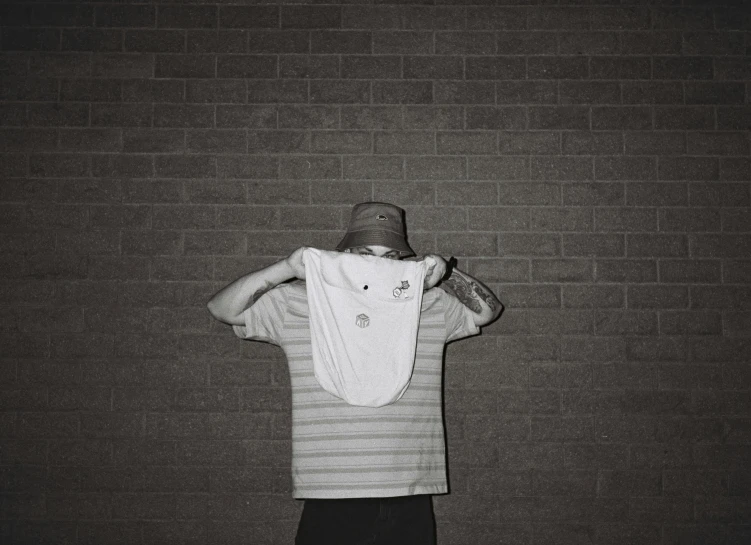 a man in front of a brick wall holding a towel