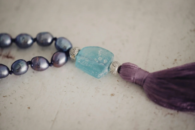 a tasseled necklace with a glass bead and blue stone