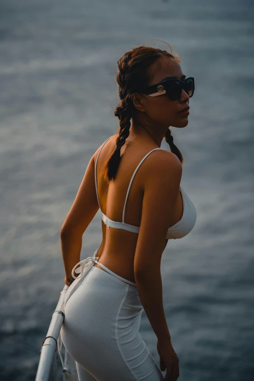 a black woman wearing a white bikini top is posing