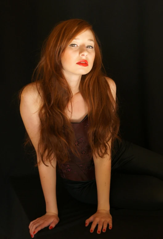 young woman with bright red lipstick poses on black background