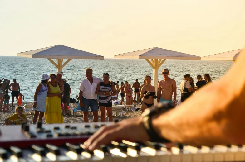 people standing around on a beach with an organ