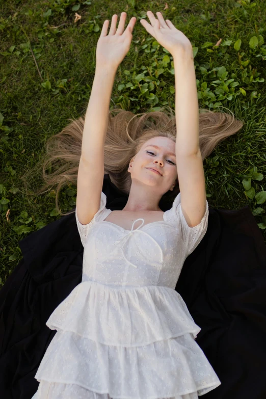 a girl is laying down on the ground holding her hands up