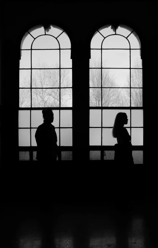 black and white pograph of a couple standing in front of two large windows