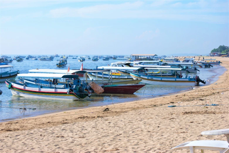 a beach full of lots of boats next to a shore