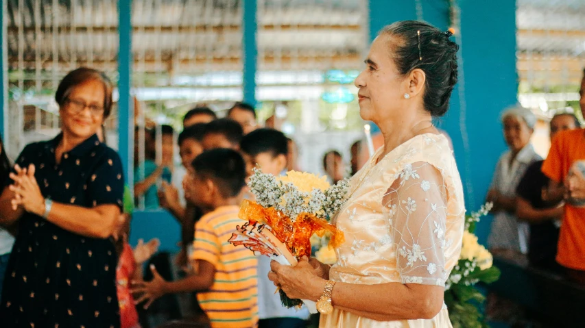 a woman holding a bunch of flowers next to another person