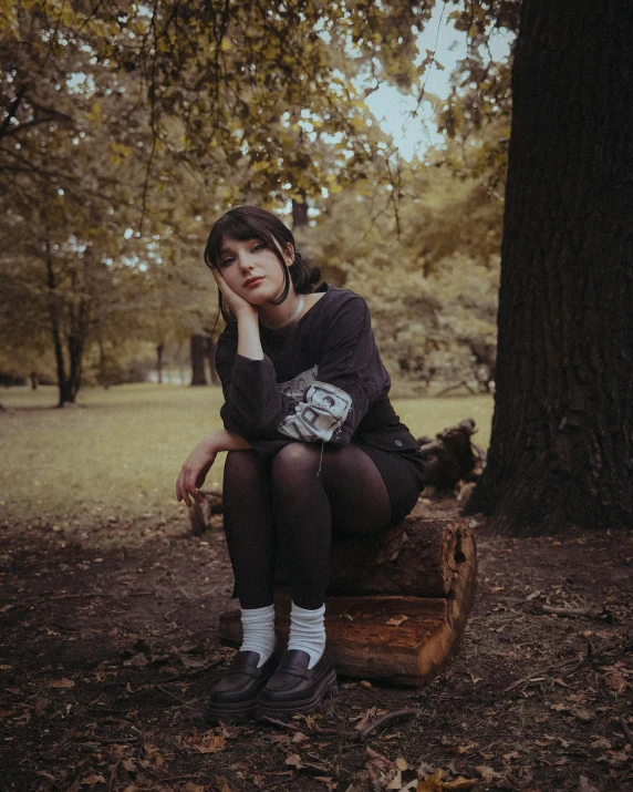 a woman is sitting on a piece of luggage in the woods