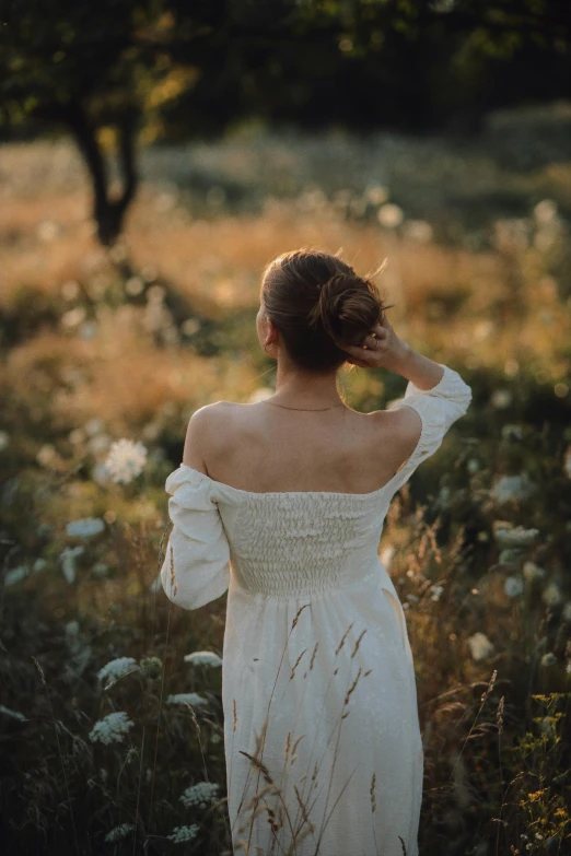 a woman stands in the middle of a field looking at flowers