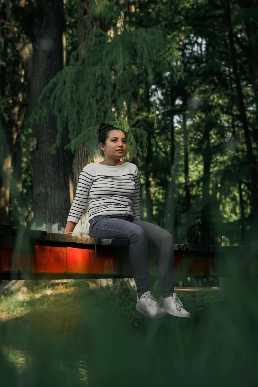a woman sitting on a wooden bench in a forest