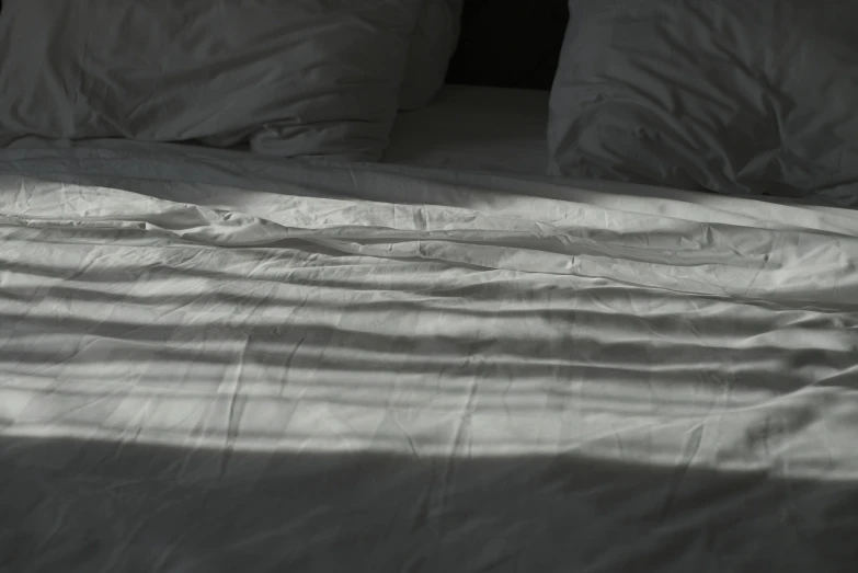 a white bed that is next to a large pillow