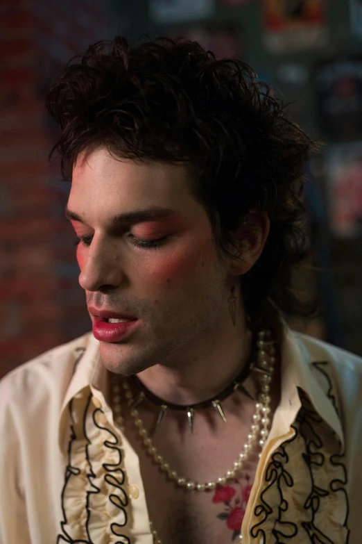 a man wearing beads and a shirt with paisley prints