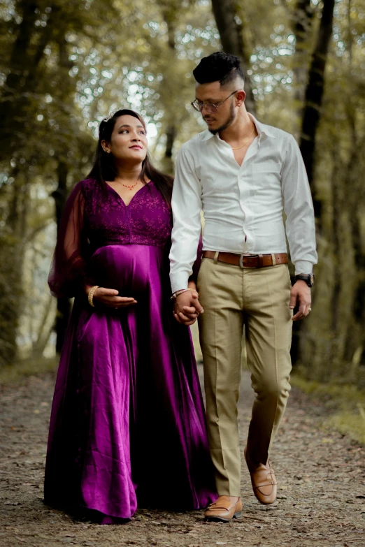 a man and woman holding hands walking through a forest