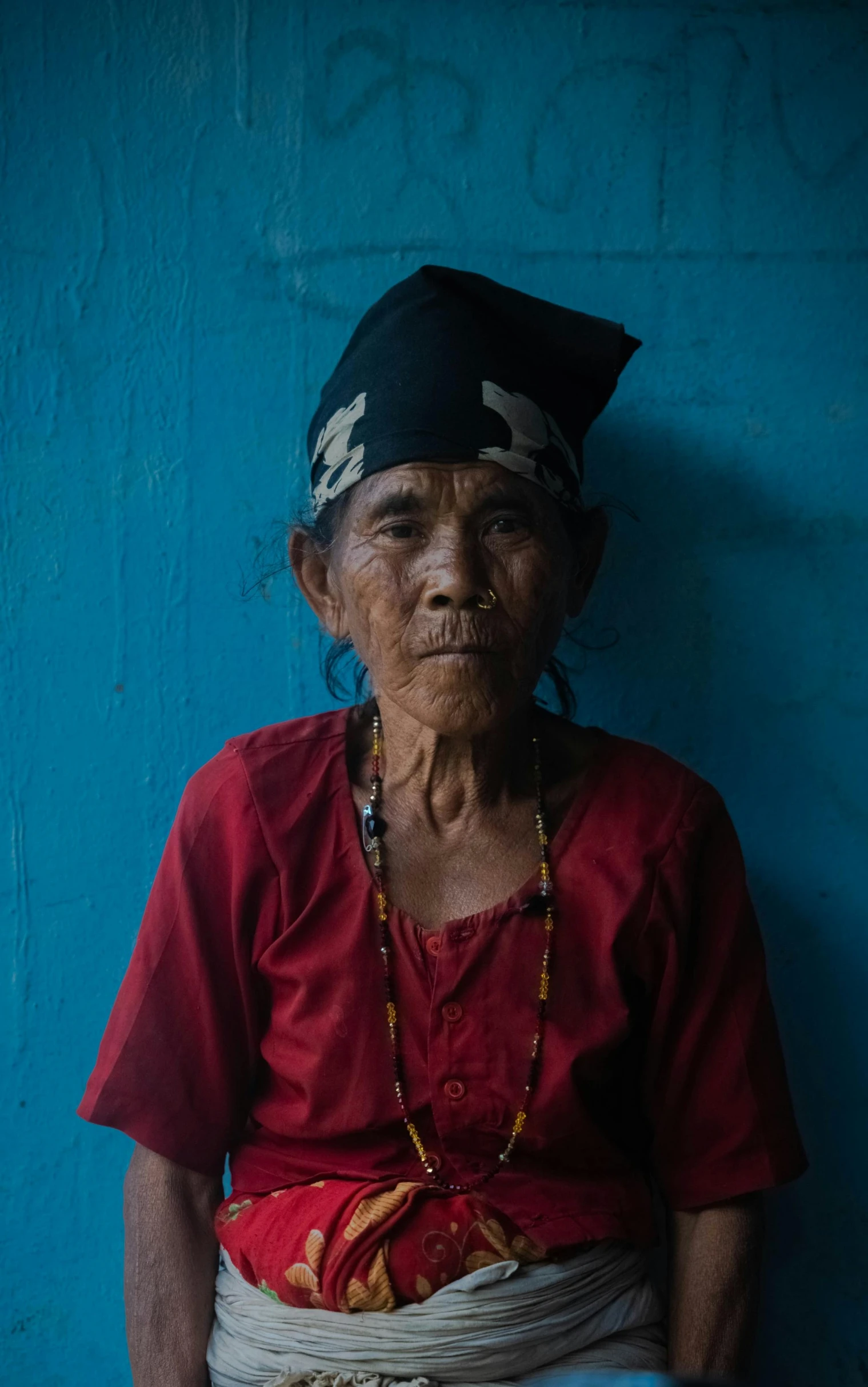 an old asian woman with necklaces wearing a head scarf