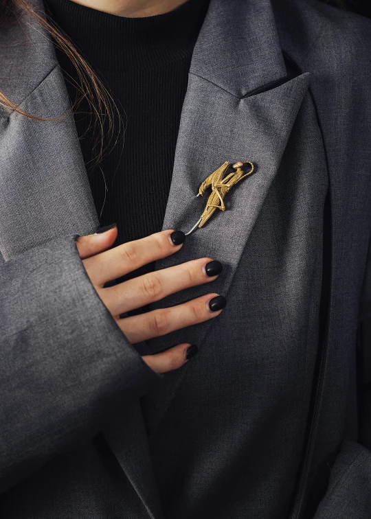 a woman in black jacket with a gold horse brooch