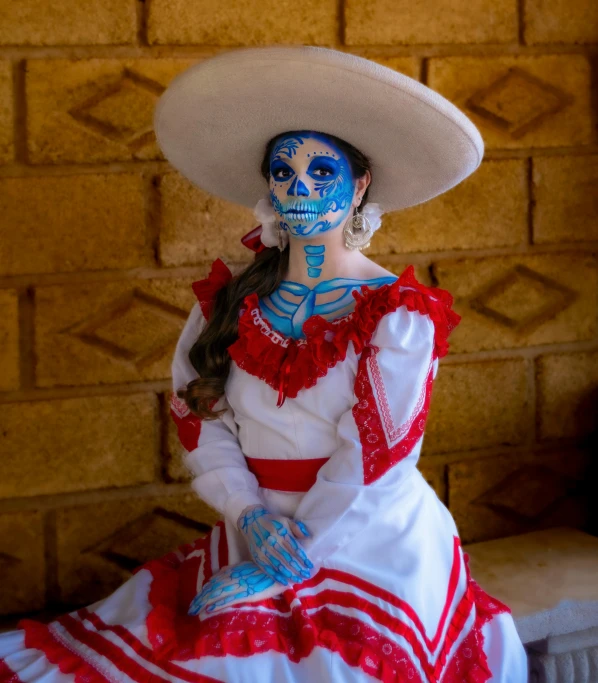 a woman in an elaborate mexican costume sitting on a bed