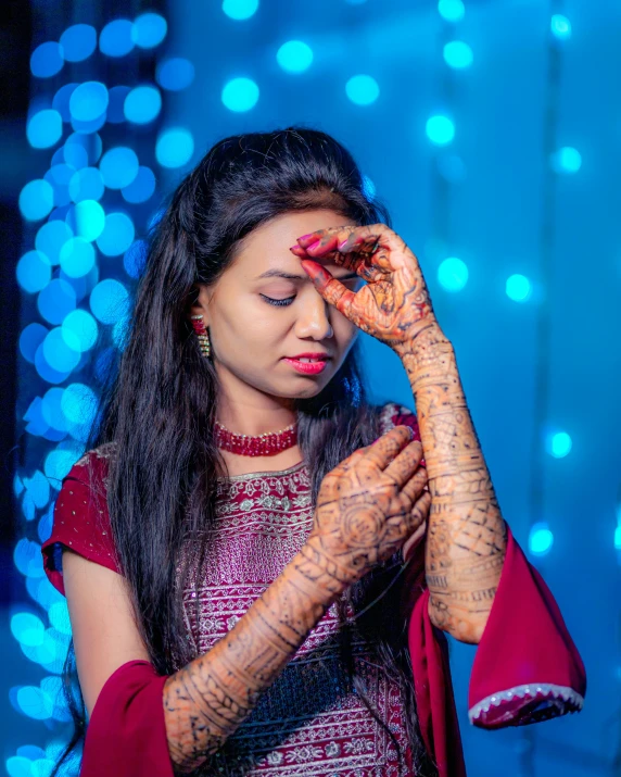 a woman wearing an indian dress is holding her hands together