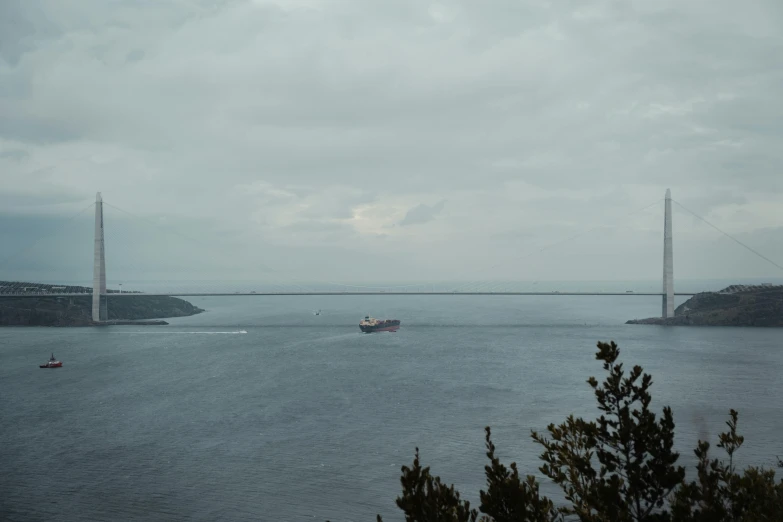 boats are riding in the water near a suspension bridge