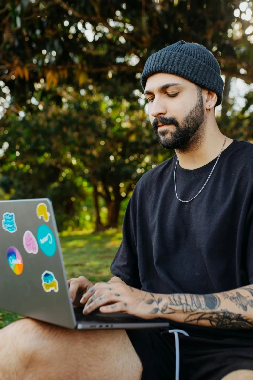 a man sitting outside on the ground using his laptop