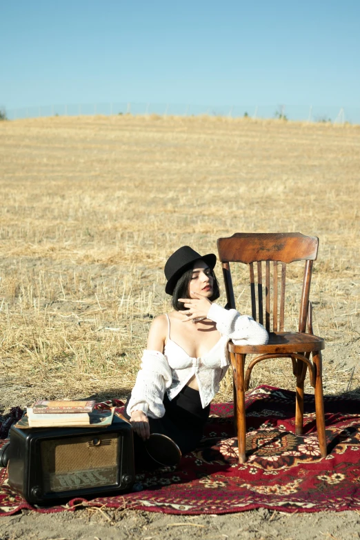 a woman sitting on the ground with a chair next to her