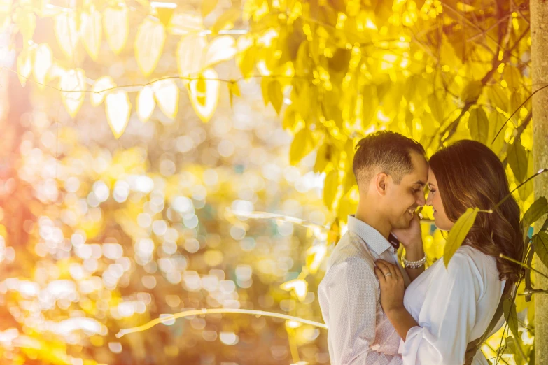 a young couple emcing under the tree nches at sunset