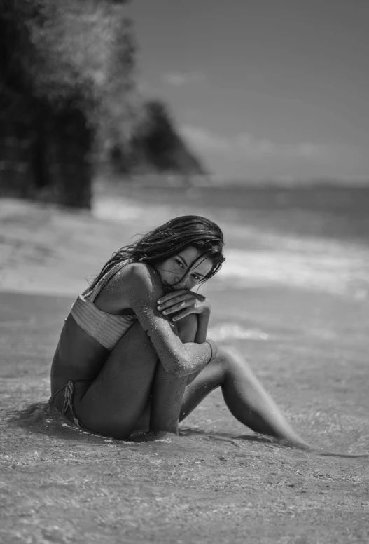 a woman sitting on top of a beach next to the ocean